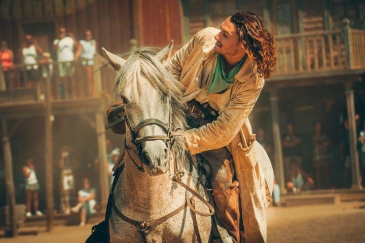 a person riding a horse in front of a statue