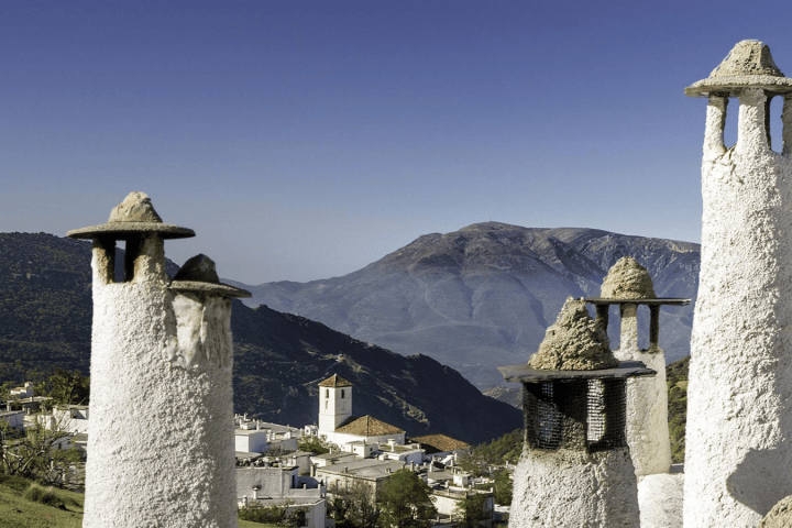 White chimneys with mountain backdrop under blue sky.